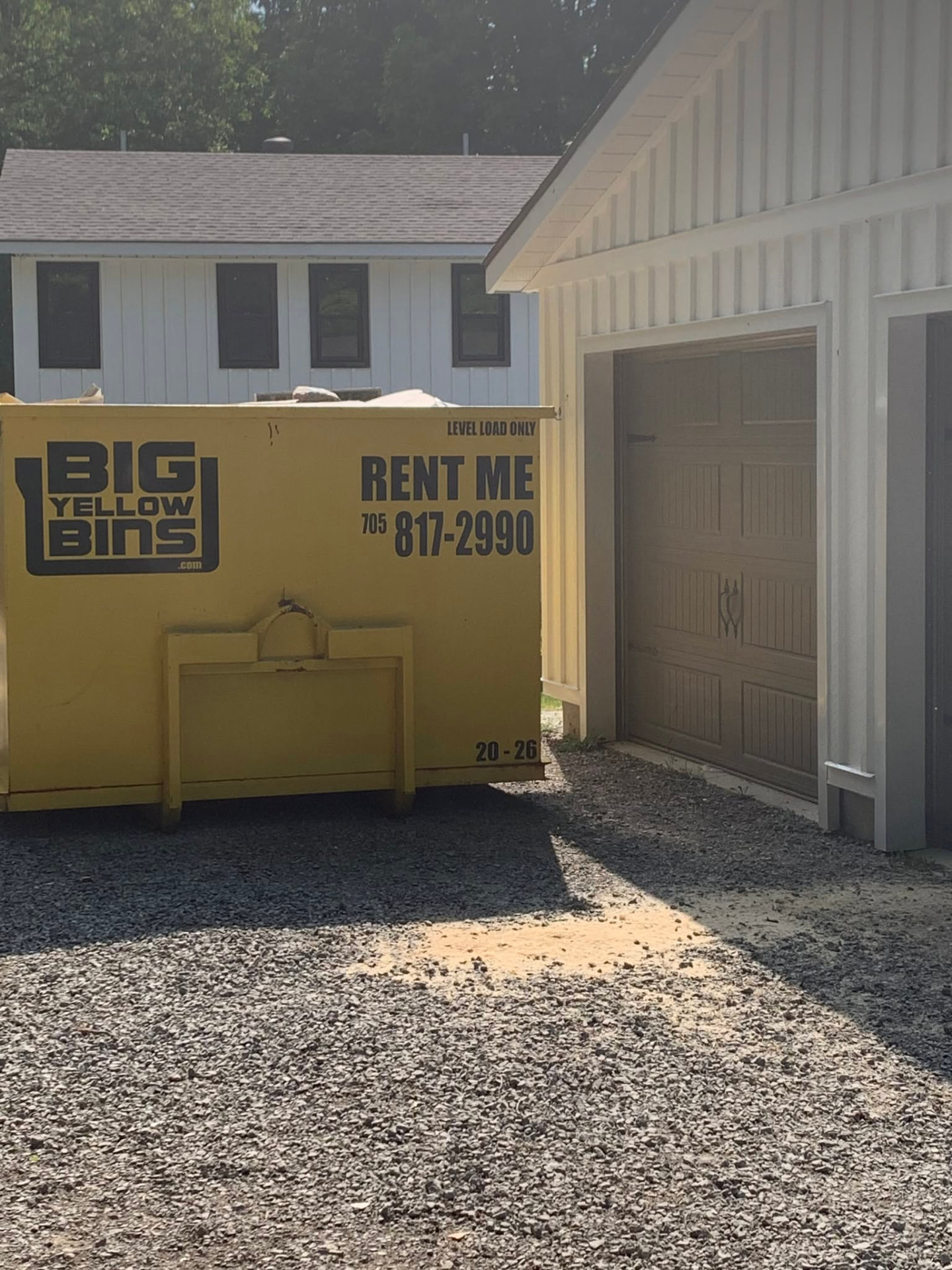 Big Yellow Bins dumpster placed beside a residential garage in Midland, Ontario